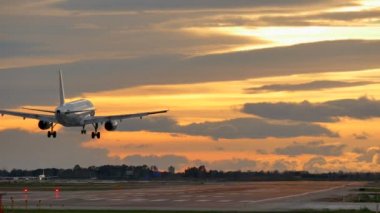 Ticari uçak günbatımında Barcelona havaalanına iniş