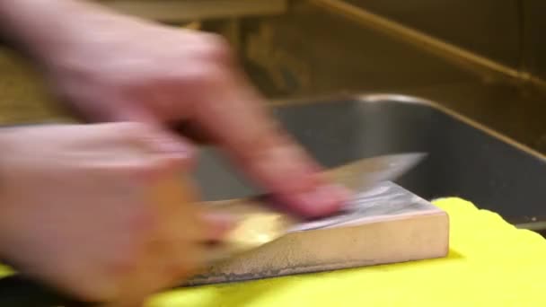 Шеф-повар суши точит свой нож розовым камнем — стоковое видео