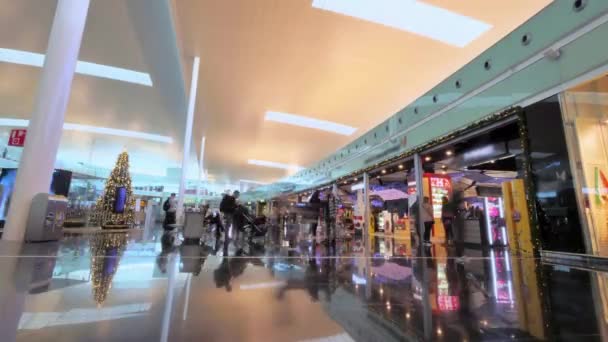 Mercado del Aeropuerto de Barcelona en Navidad. Hall de la zona comercial del aeropuerto durante la Navidad. Moderna tienda de centro comercial del aeropuerto con turistas. Tiendas de lujo en la terminal del aeropuerto . — Vídeos de Stock