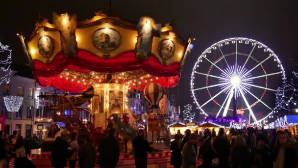 Feria tradicional de Navidad en Bruselas. Típico carrusel girando y ahumado.Ambiente de Navidad en el centro de la ciudad de Bruselas.Gran feria de Navidad iluminada lleno de gente . — Vídeos de Stock