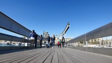 Barcelona'da geçiş Maremagnum pazarı Köprüsü. Teknelerden ve spor tekne ile kolon heykeli anıt liman. Cityscape Barcelona Port Vell bölgesindeki. Barselona bölgesindeki yaz aylarında yürüyüş turistler. Maremagnum pazar yeri Simgesel Yapı.