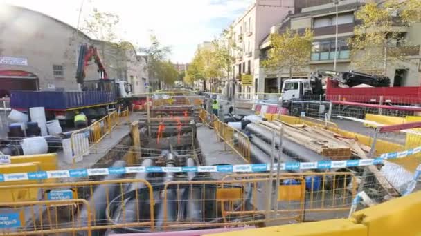 Bauarbeiten auf den Straßen der Innenstadt von Barcelona Kamerawagen. Bau der Zukunft der barcelona smartcity. Steter Kameramann von Baumaschinen und Arbeitern. Installation einer Hauptwasserleitung im Untergrund der Stadt. — Stockvideo