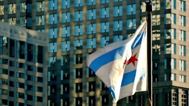 映画シカゴの旗が夕日に手を振ってします シカゴ市内中心部のゴールデン マイルにフラッグ スタッフ シカゴのフラグが風の強いシカゴの街で手を振っています 高層ビルのガラス Windows の背景とフラグします — ストック動画