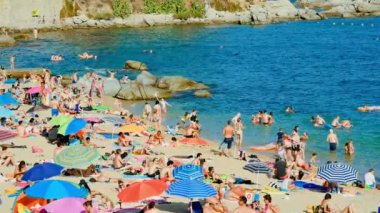 Yaz aylarında tatil İspanya sahilde. Yaz günü tipik Akdeniz beach. Sahilde tatil insanlar görüntüleyin. Boş zaman sahilde sırasında turkuaz berrak suları. Sahilde tatil sahne. Güneşlenmek sahne olan.