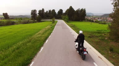Onun Enduro motosiklet sürüş bir Curvy yolda motosikletçi. Genç bir adam onun spor motosiklet bahar ile hava dron vurdu. Katalonya manzaralı bir yolda eylem motosiklet çapraz.