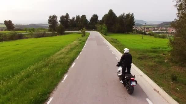 摩托车司机驾驶他的复古摩托车在弯曲的道路上 空中无人机拍摄的一个年轻人与他的运动摩托车在春季 在加泰罗尼亚一条风景秀丽的道路上交叉摩托车的行动 — 图库视频影像