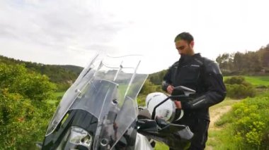Motosikletçi onun spor motosiklet yol egzersiz için hazırlanıyor. Genç bir adam onun enduro motosiklet baharda başlamak üzere bir sabit cam kadeh. Düşük açılı tekerlekteki görünümü onun kask ve eldiven giymeyi bir sporcu.