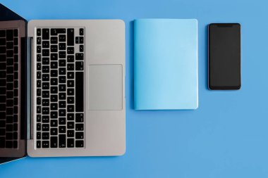 Mavi arka planda dizüstü bilgisayar. Laptop ve şişe mavi arka planda. Laptop telefonu ve mavi arka planda not defteri. Laptop telefonu, not defteri ve mavi arka planda şişe.. 