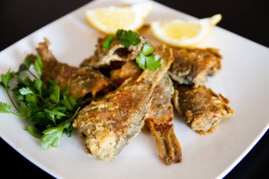Beyaz tabakta kızarmış balık. Limonlu ve maydanozlu ızgara..