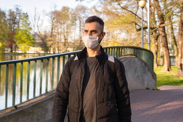 Parktaki maskeli adam. Telefonu olan bir adam parkta yürüyor..