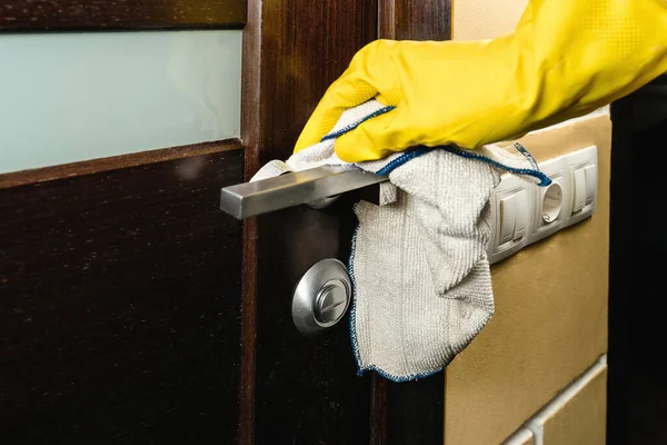 Desinfectie van het appartement. Een man in handschoenen veegt de deurklink schoon. Stockfoto