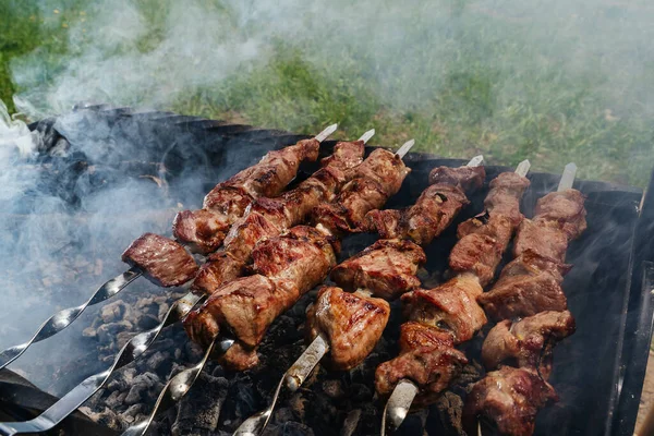 Shish kebab from a pork neck on skewers is prepared on coals in the grill — Stock Photo, Image
