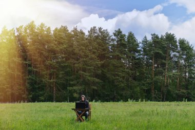 Boş bir tarlada dizüstü bilgisayarla çalışan bir adam. Sahada uzak çalışma