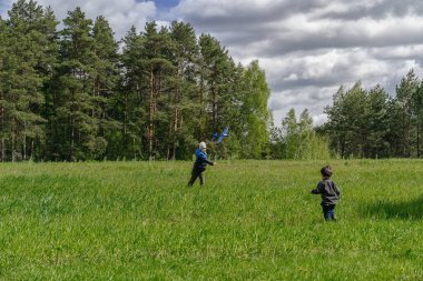 Çocuklar yeşil bir alanda uçak oynuyorlar. Uçağın mavi modeli.. 