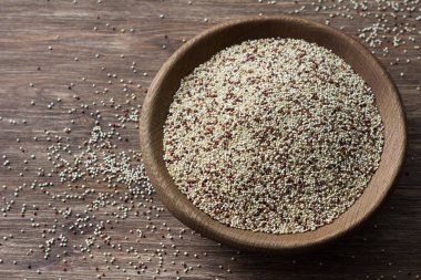Ahşap masa üzerinde ahşap kase karışık ham quinoa