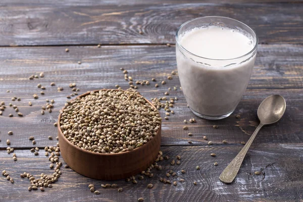 Hemp seeds in a wooden bowl and hemp milk on a wooden background