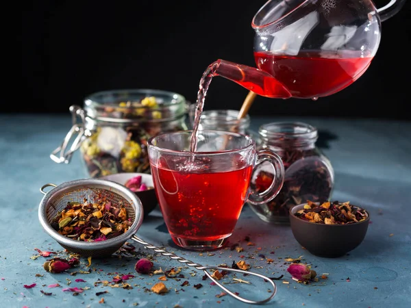 Process brewing tea,tea ceremony,Cup of freshly brewed fruit and herbal tea, dark mood.Hot water is poured from the kettle into a cup with tea leaves.