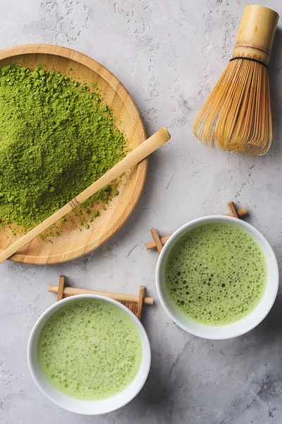 Matcha green powder and tea on gray concrete background