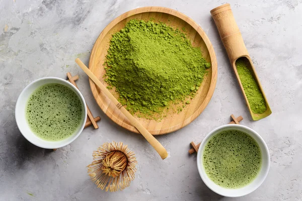 Matcha green powder and tea on gray concrete background