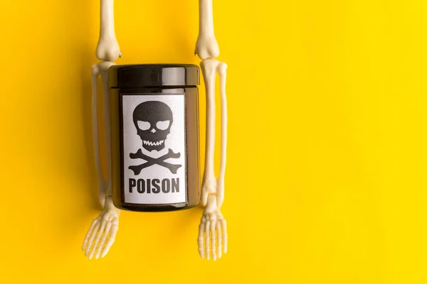 Concept of poison, toxic substances, drug overdose, lethal dose,glass jar with skull and crossbonesl and skeleton on yellow background,copy space