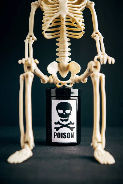 Concept of poison, toxic substances, drug overdose, lethal dose,glass jar with skull and crossbonesl and skeleton on dark background