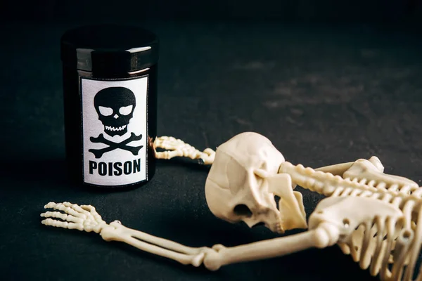 Concept of poison, toxic substances, drug overdose, lethal dose,glass jar with skull and crossbonesl and skeleton on dark background,copy space
