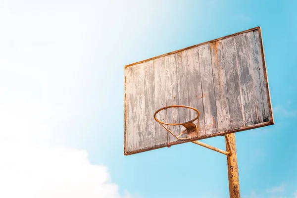 Vintage old basketball Hoop with a wooden Board with peeling paint on the background of blue sky