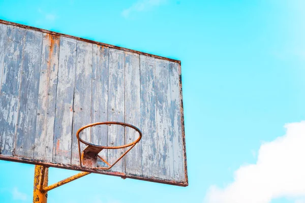 Vintage old basketball Hoop with a wooden Board with peeling paint on the background of blue sky