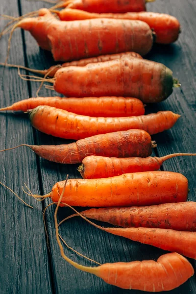 Fresh raw authentic ugly carrots on dark background, harvesting