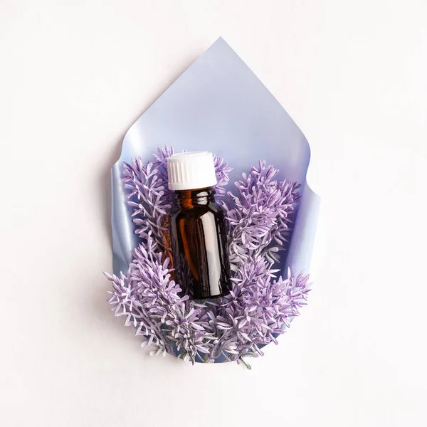 Lavender fragrance oil with lavender flowers in a glass bottle in a purple bag on a white background