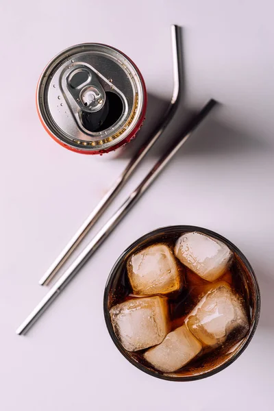 Can with carbonated soda and a glass glass with ice ,metal reusable straws for cocktail on white background