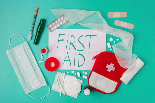 Creative layout of medicines for first aid, first aid kit for tourists, bandages, painkillers, plaster.cotton wool, cotton sticks, tampons on a turquoise background