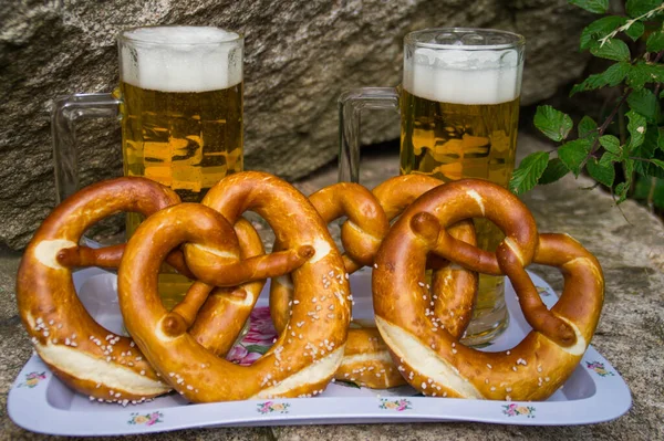 beer with a pretzel stands on a countertop by the stones. 4 pretzels, two glasses of beer. festivities, initially the holiday was organized and held privately. Salty pretzel - a traditional German app