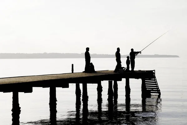 Místní rybáři loví ryby z mola. Chození do společnosti s frien — Stock fotografie