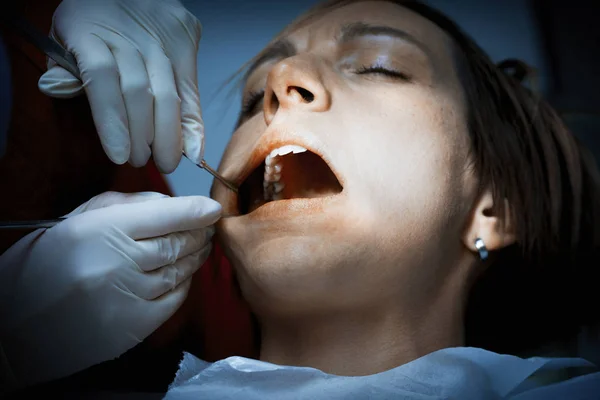 Dentist examining a patients teeth before oral surgery at the de — Stock Photo, Image
