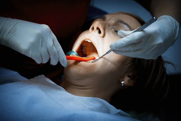 Dentist examining a patients teeth before oral surgery at the de — Stock Photo, Image