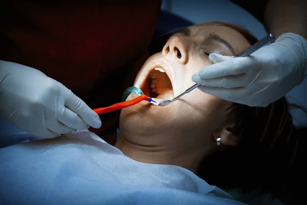 Dentist examining a patients teeth before oral surgery at the de — Stock Photo, Image