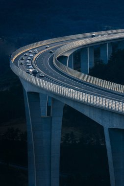 Küresel ulaşım ve lojistik bağlantı. Modern ve gelecekçi otoyolda yoğun trafik var. Yüksek eğimli köprü, günbatımında mühendislik başyapıtı.