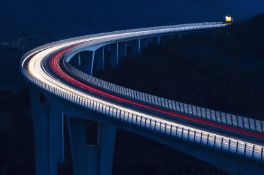 Küresel ulaşım ve lojistik bağlantı. Modern ve gelecekçi otoyolda yoğun trafik var. Yüksek eğimli köprü, günbatımında mühendislik başyapıtı.