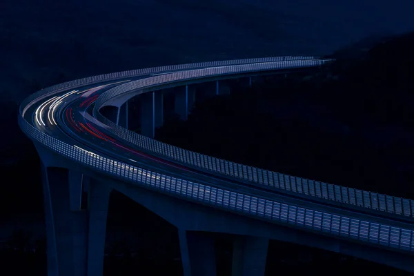 Global transport and logistics connection. Heavy traffic on the modern and futuristic highway. High curved bridge, engineering masterpiece in the sunset.