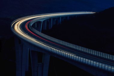 Küresel ulaşım ve lojistik bağlantı. Modern ve gelecekçi otoyolda yoğun trafik var. Yüksek eğimli köprü, günbatımında mühendislik başyapıtı.