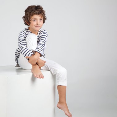Beyaz arka plan üzerinde oturan küçük moda çocuk. Sevimli ve c