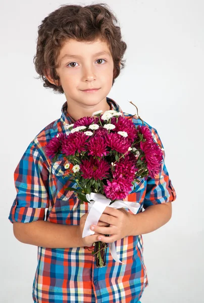 Menino cheirando com buquê de flores no fundo branco . — Fotografia de Stock