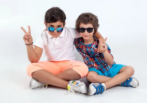 Duas crianças de moda sentadas sobre fundo branco em óculos de sol — Fotografia de Stock