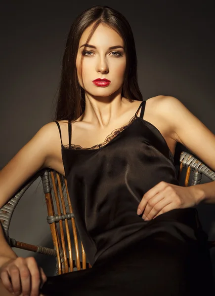 Elegante donna di lusso in pizzo di seta vestito nero seduto sopra scuro — Foto Stock