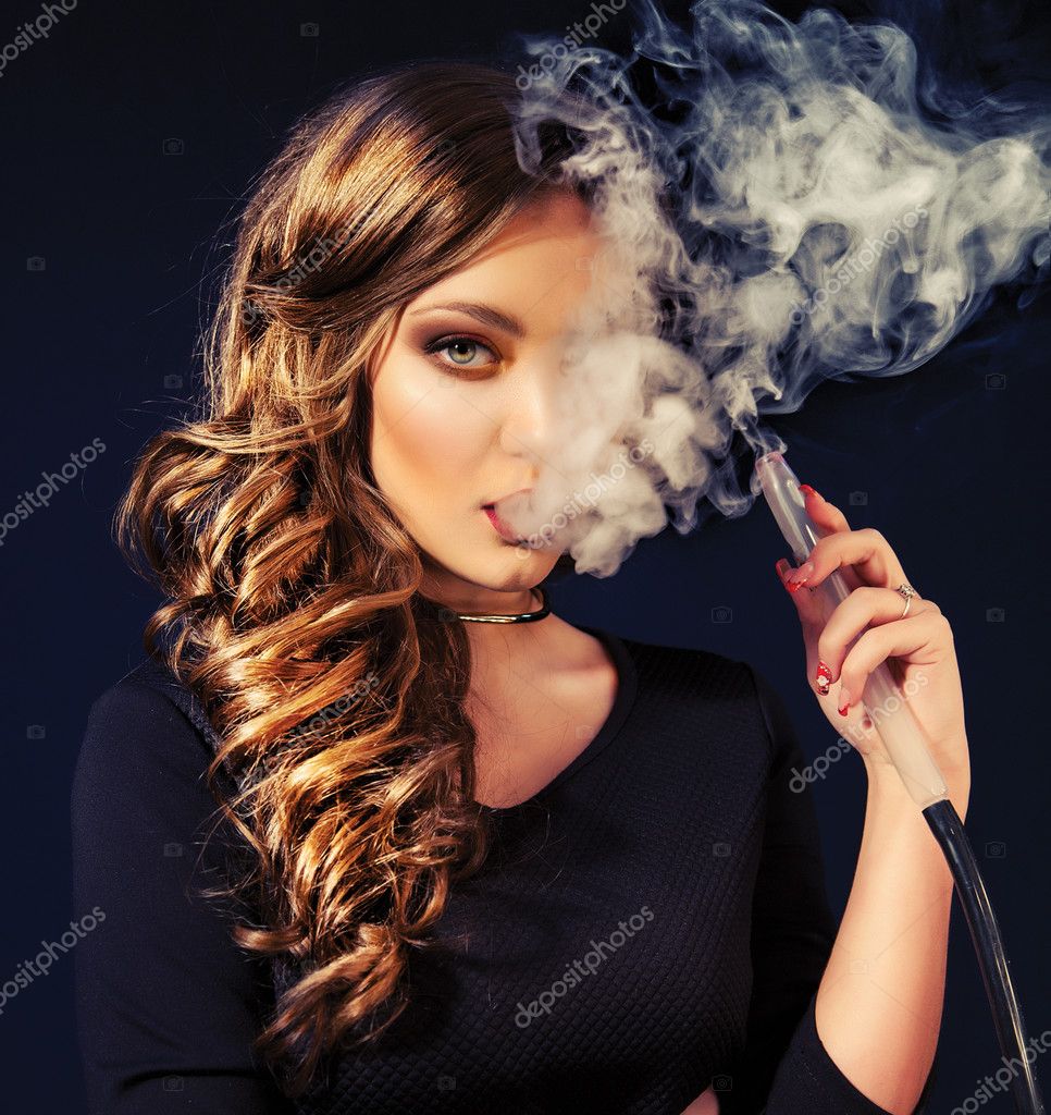 Young, beautiful girl in club dress and perfect make up smoke a ...