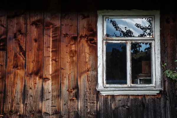 Het venster van de oude houten blokhuis op de achtergrond van hout — Stockfoto