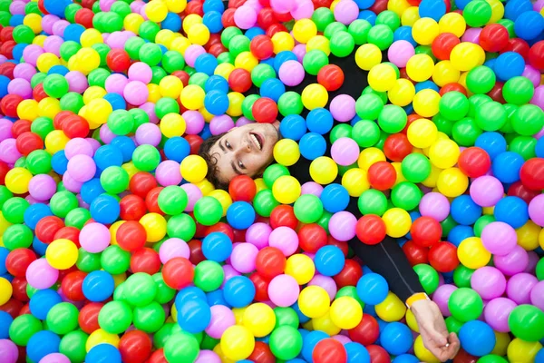 Jovem feliz e engraçado ralaxing em muitos bals coloridos lembrar — Fotografia de Stock