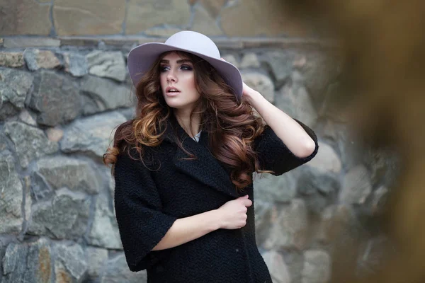 Luxe elegante vrouw in trendy zwarte jas en hoed standinf in de buurt van — Stockfoto