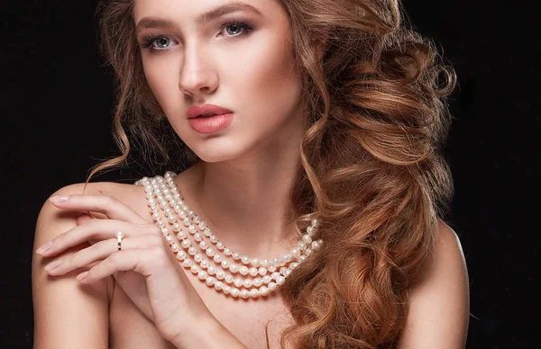 Beautiful elegant woman in pearl necklace, long curly tress over
